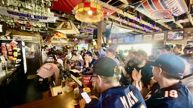 A crowded bar full of Chicago Bears fans watching a daytime game in a bar densely decorated with sports memorabilia