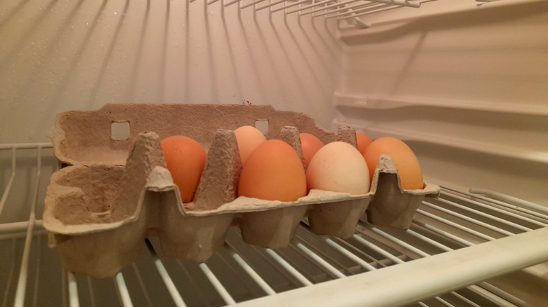 brown chicken eggs in a cardboard carton inside a refrigerator