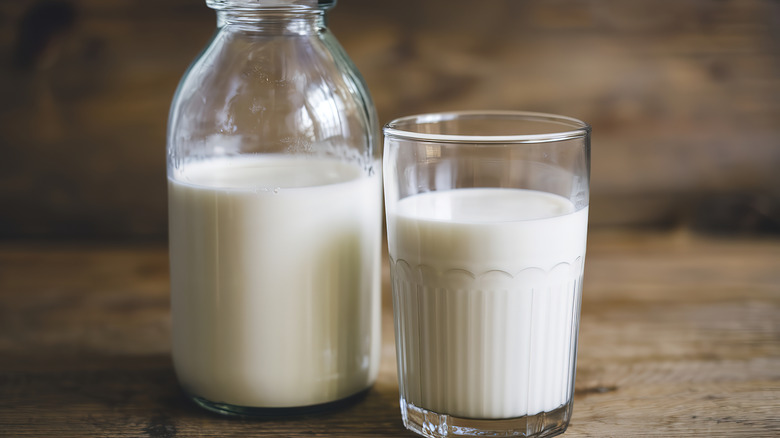 A jar of creamy milk (half and half) next to a glass of half and half