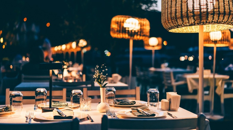 An outdoor table set for four guests with dim lighting.
