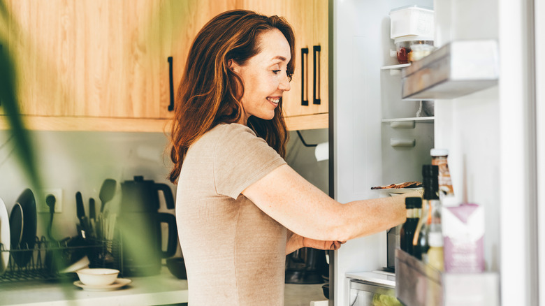Woman removing food from the refrigerator while smiling
