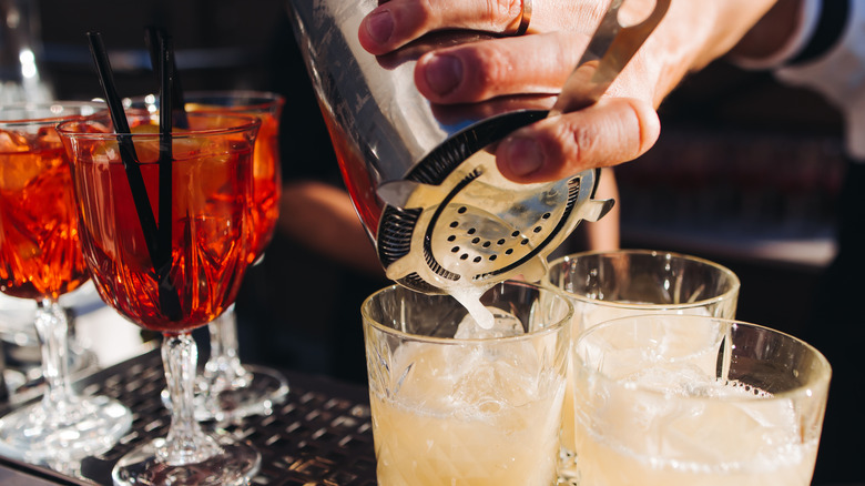 A bartender prepares several drinks at the bar