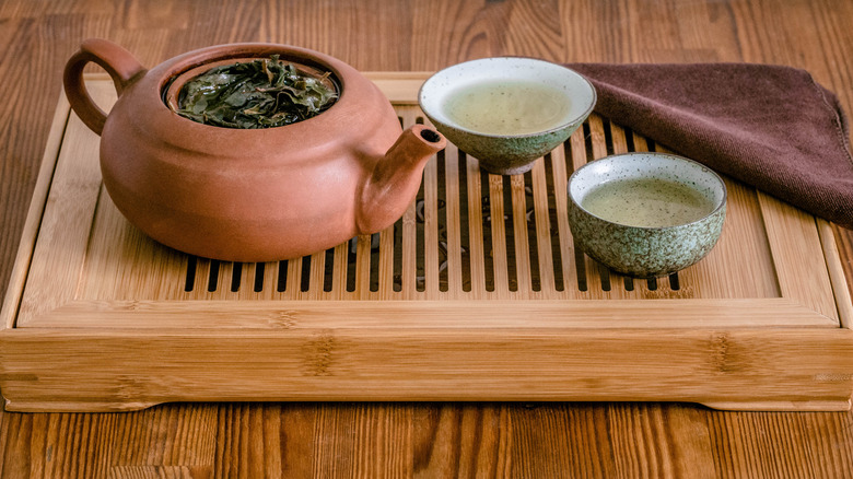 Loose-leaf tea in a small clay teapot with two small bowls