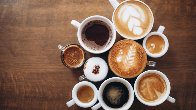 Different kinds of coffee in cups on a wooden table