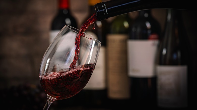 A fancy looking red wine being poured into a glass.