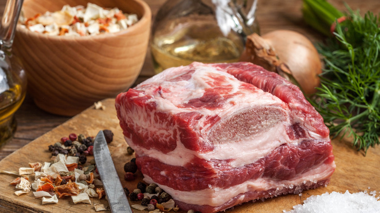 A raw brisket on a cutting board with salt and pepper surrounding