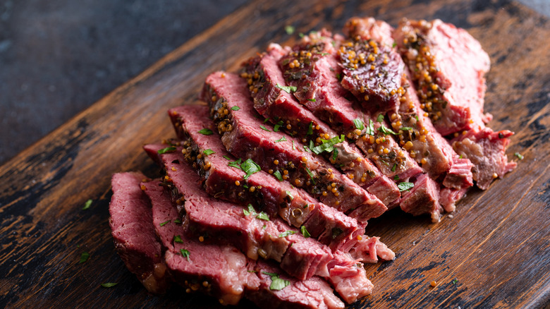 Sliced, cooked corned beef on a wooden cutting board