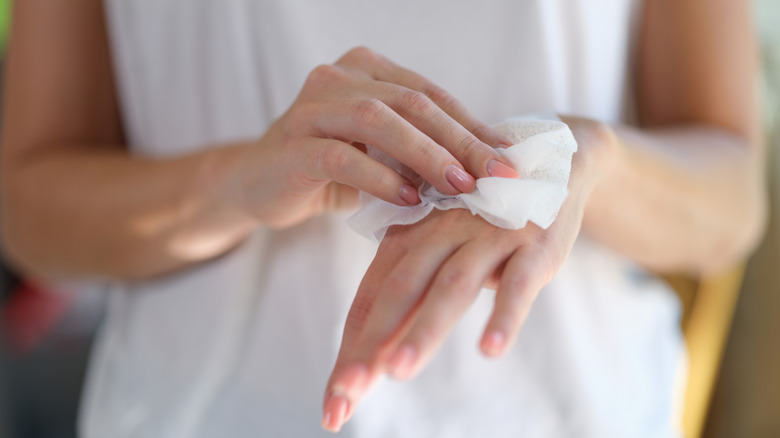 A person cleaning their hands with an antibacterial wipe.