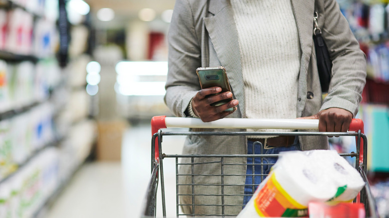 A person pushing a grocery cart through a store.
