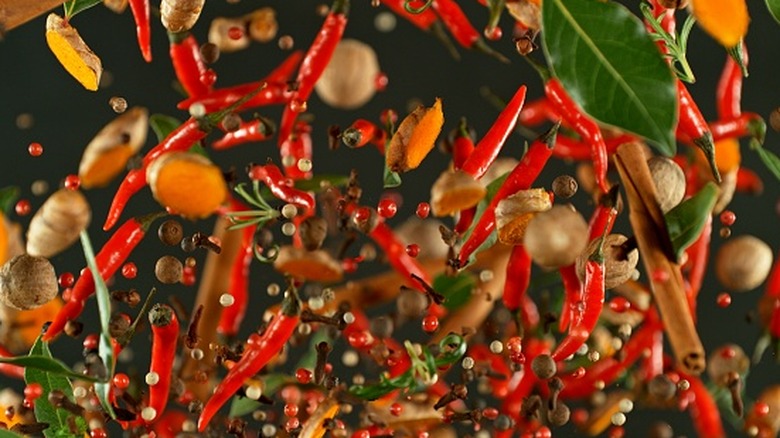 Various spices and peppers are flying through the air