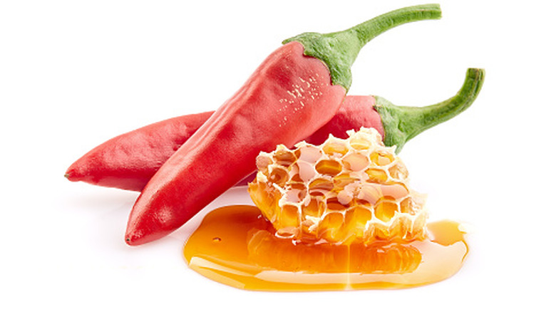 Hot chili peppers and honey rest on a white background