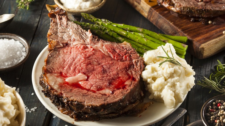 Slice of prime rib on plate with mashed potatoes and asparagus