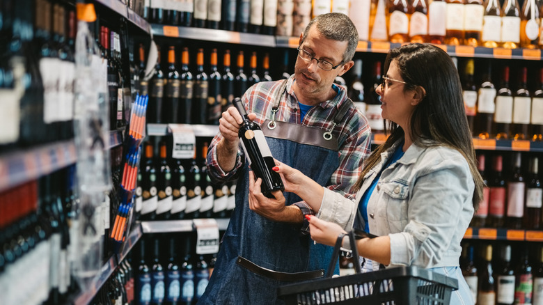 A woman gets help deciding which wine to buy