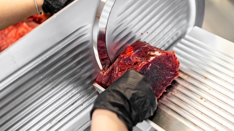 Person slicing beef on meat slicer
