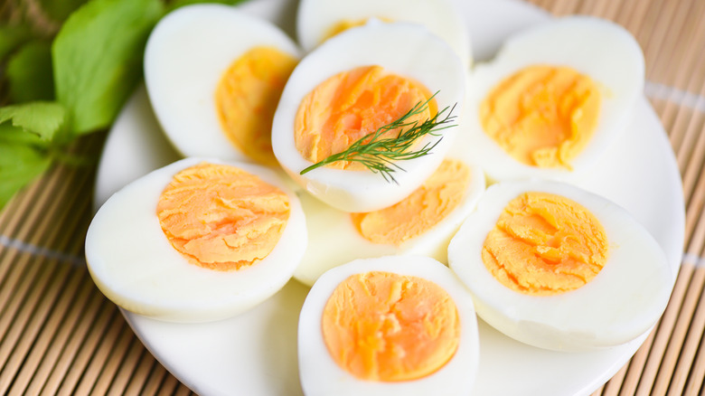 A plate of hard boiled eggs cut in half and garnished with dill.