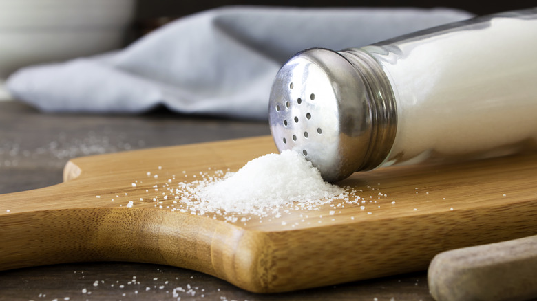A salt shaker spilled onto a board