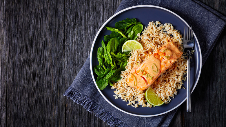 Salmon brown rice and greens served on a plate