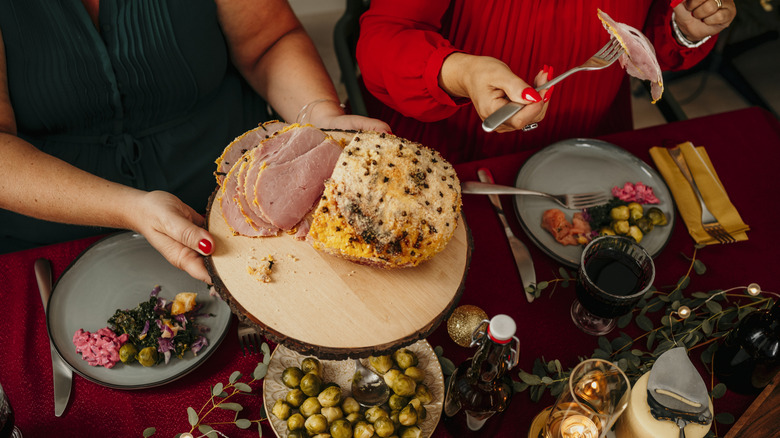 Women serve themselves Christmas ham at a dinner table