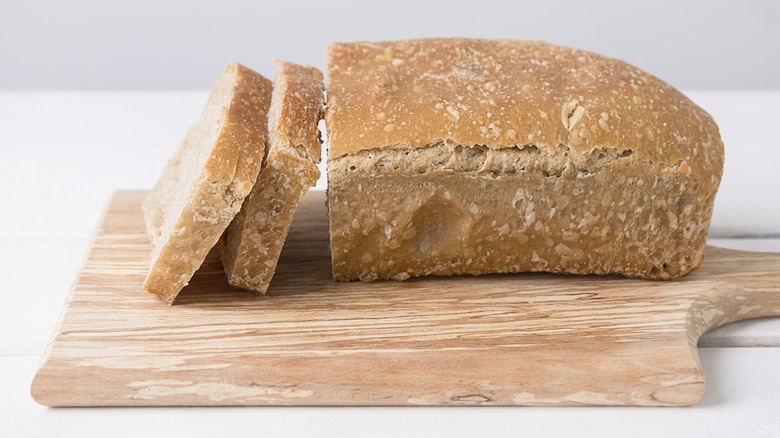 Partially sliced loaf of homemade bread on a wooden board