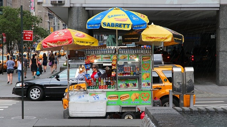 New York hot dog cart set up on the side of the road.