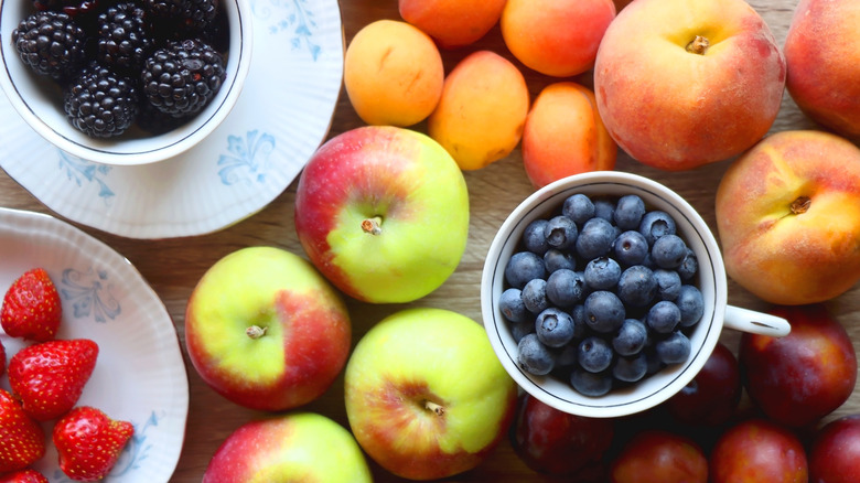 Fresh apples, peaches, and berries in bowls