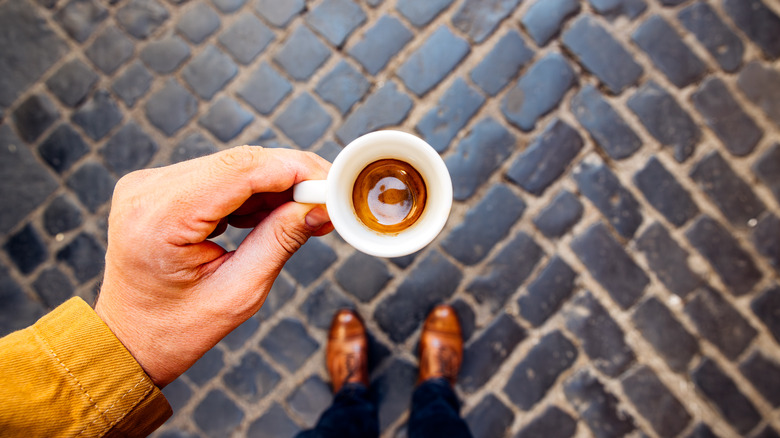 A man holding his cup of espresso, showing off the crema.