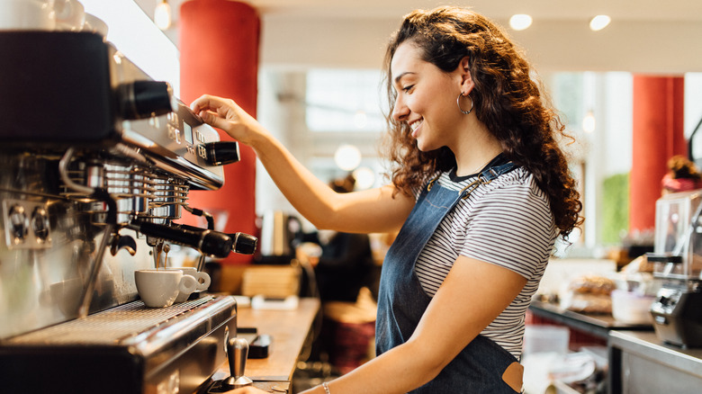 A happy barista making drinks for customers.