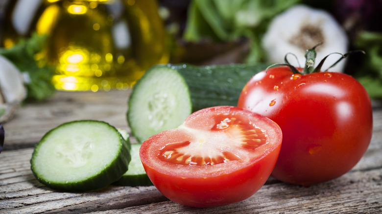 A sliced cucumber and tomato on a wood table