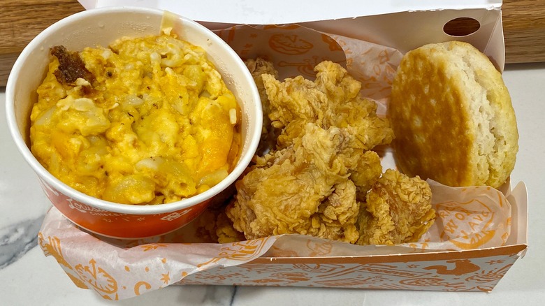 Box of fried chicken with a biscuit and tub of macaroni and cheese