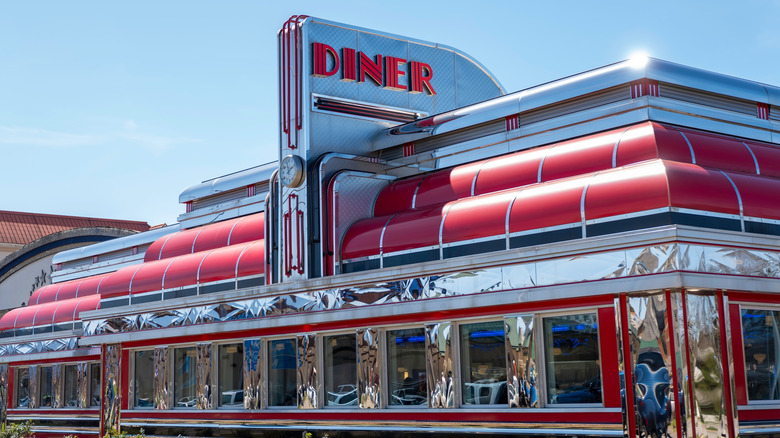 Exterior of a classic chrome diner with rounded red rooflines, and a large diner sign above the entrance.
