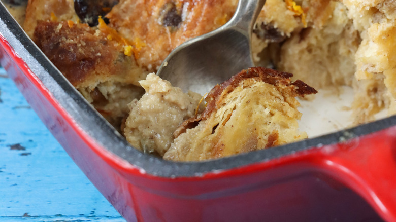 Close-up of a spoon dipping into a tray of bread pudding