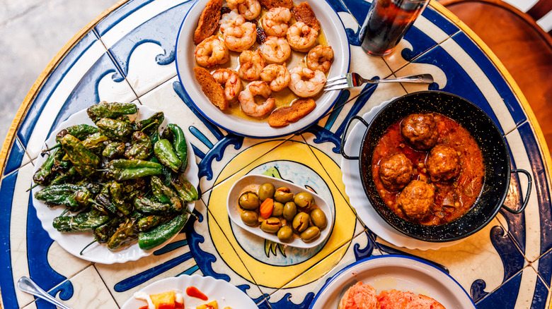 Tapas-style setup with shrimp, roasted peppers, and meatballs
