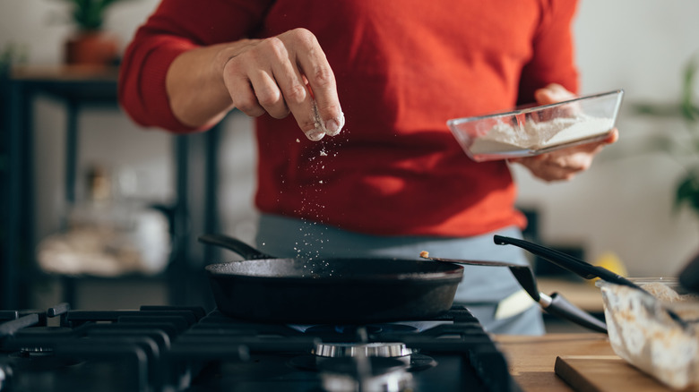 Man adding salt to a pan with his fingers