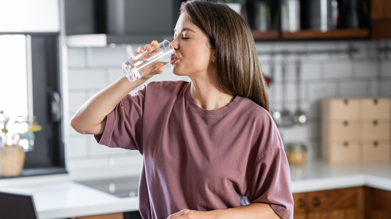 Woman drinking a glass of water in the kitchen