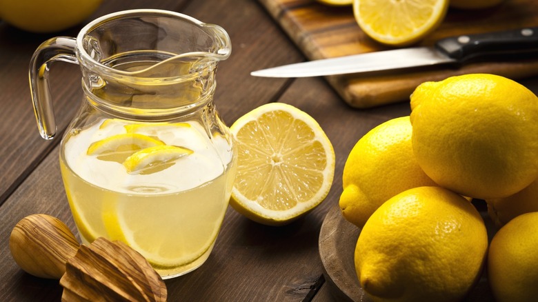 A pitcher of American-style lemonade next to a bowl of lemons.
