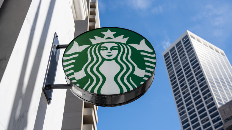 A Starbucks sign on the side of a building with blue sky