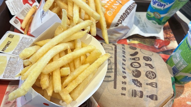 A Burger King order with fries, sauce, burgers, and drinks on a dining tray.