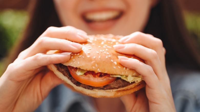A woman eating a fast food hamburger.