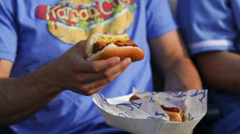 A fan eating a hot dog in a baseball stadium