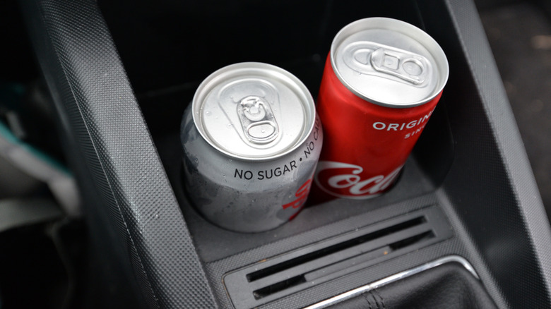 Coke cans sitting in a car's cup holder