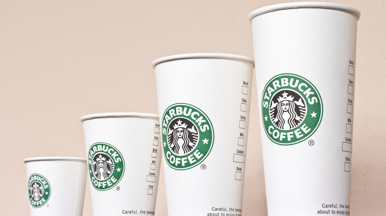 Four different sizes of Starbucks cups with no lids on them.