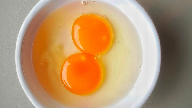 Two raw eggs in a white bowl