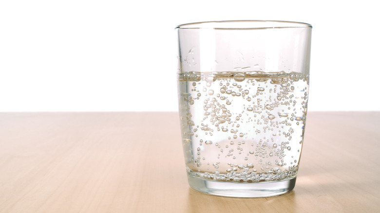 A glass of seltzer water sitting on a table.