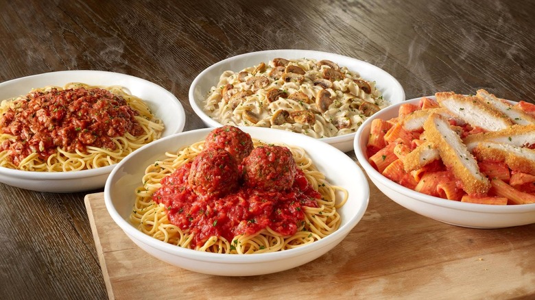 Four pasta bowls from Olive Garden sitting on a table next to each other.