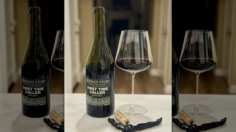 an uncorked bottle of Herman Story First Time Caller Wine, some poured into a glass