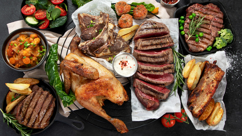 Top view of assorted cooked meats including chicken, steak, beef roast, and meatballs.