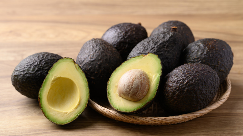 A bowl of whole and halved avocados