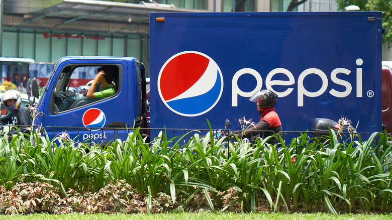A Pepsi truck in the Philippines on a plant-lined busy road