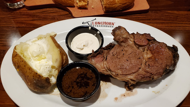 Steak and a baked potato on plate at Longhorn Steakhouse.