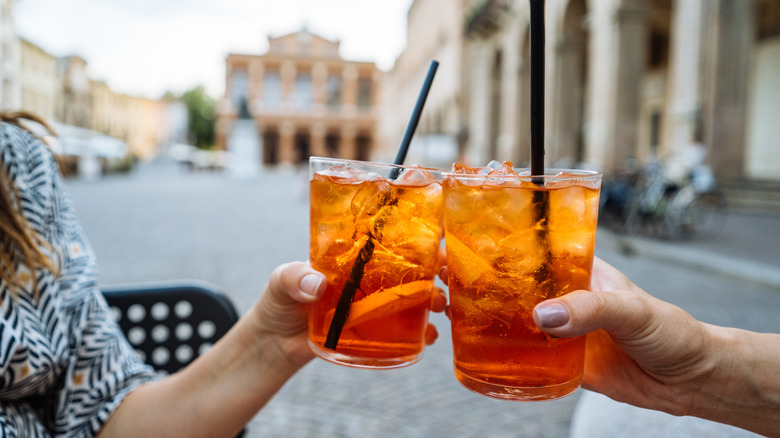two people holding campari cocktails, cheersing